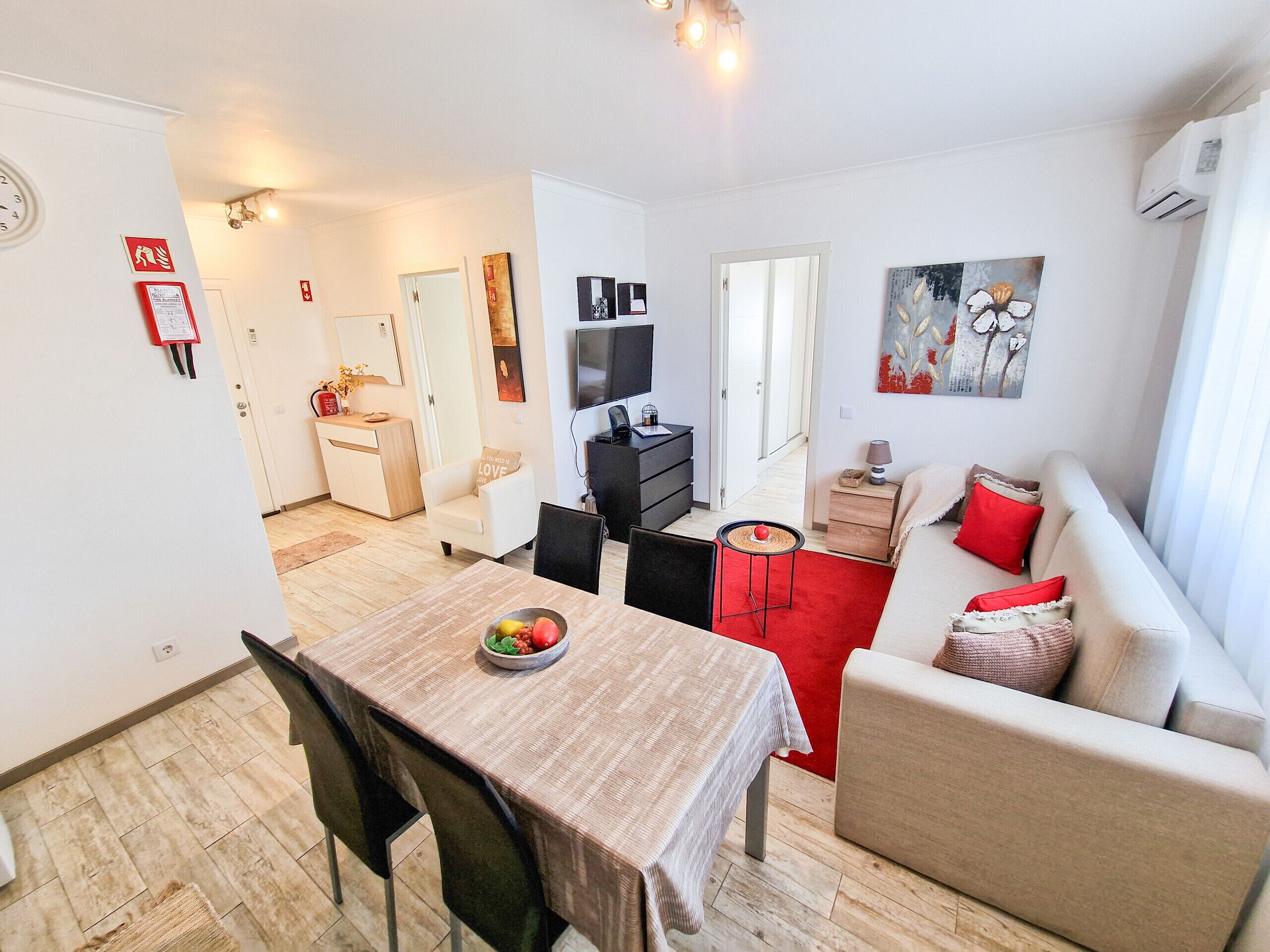 A modern living room with a dining area, a sofa, a TV, and a red carpet.
