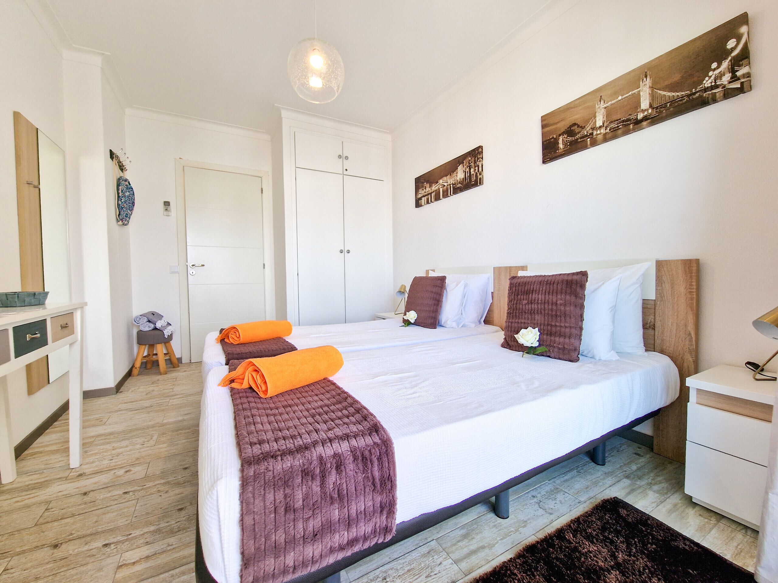 A bedroom with a large bed, a wooden headboard, a bedside table, a nightstand, a mirror, and a door.