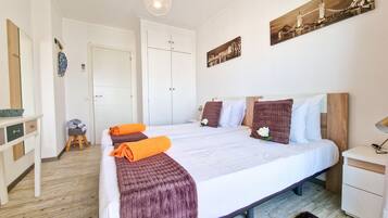 A bedroom with a large bed, a wooden headboard, a bedside table, a nightstand, a mirror, and a door.