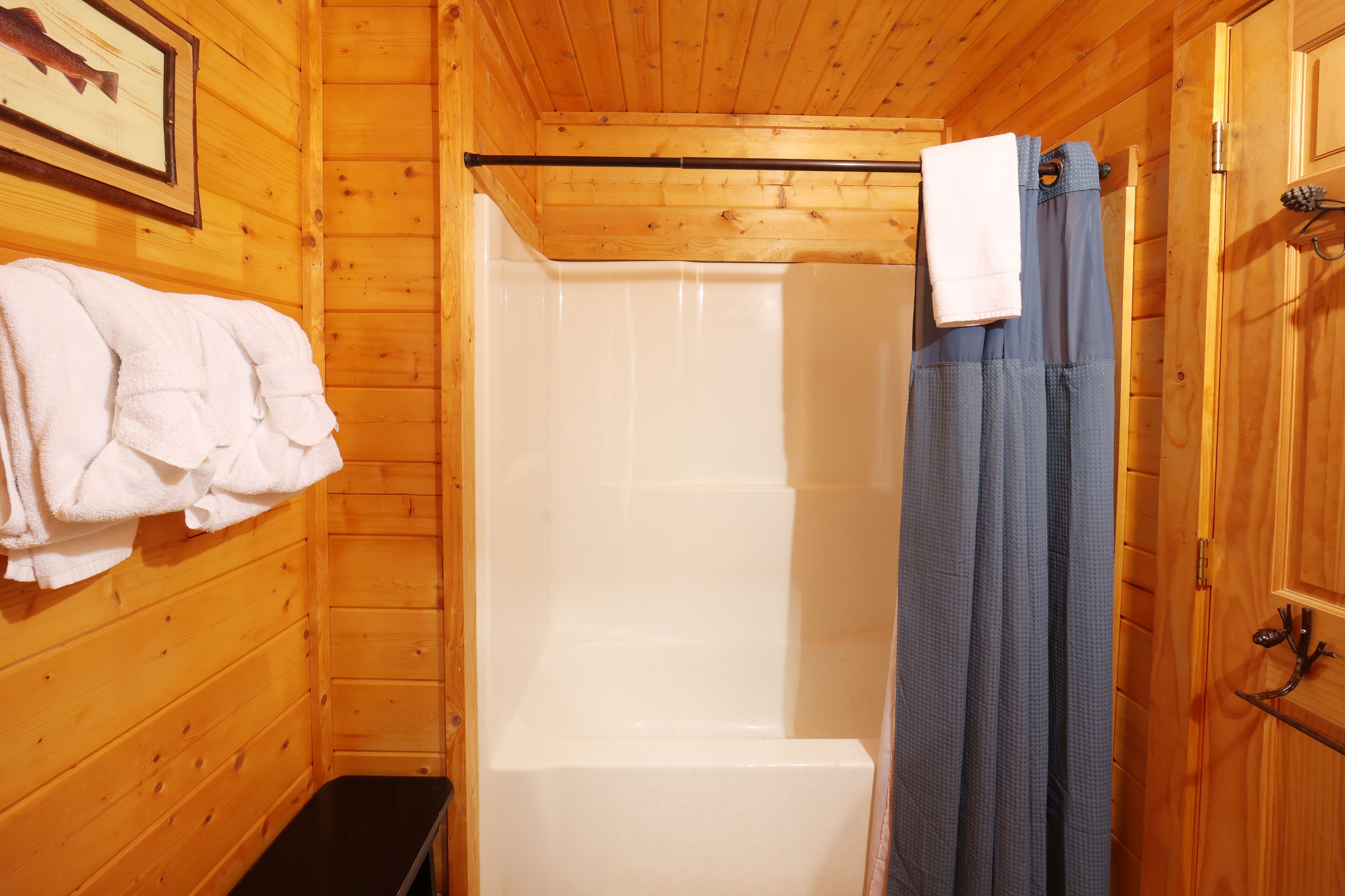 Bany d'una cabana de fusta amb banyera, cortina de dutxai una panxa.