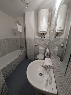 Une salle de bain équipée d’une baignoire, de toilettes, d’un lavabo et d’un miroir.