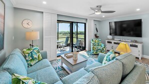 A living room with a sofa set, a TV, and a view of the outdoors.