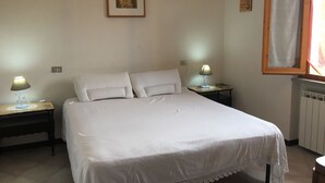 A bedroom with a large bed, two bedside tables with lamps, a framed picture on the wall, and a window with a curtain. - The House Of Antonella Casentino, Arezzo, Tuscany, Italy  (Subbiano)