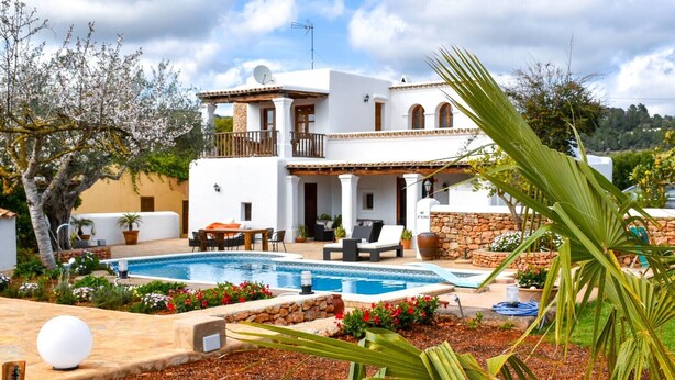 A two-story white villa with a pool, outdoor seating, and a stone wall. - CASA LAS DALIAS (San Carlos/ Sant Carles de Peralta)