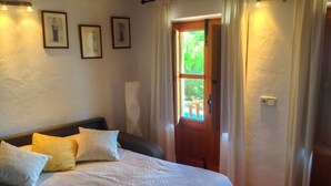 A bedroom with a bed, pillows, a wooden door, and a window. - CASA LAS DALIAS (San Carlos/ Sant Carles de Peralta)