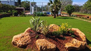A well-maintained garden with large rocks, a lawn, and a pool area. - CASA LAS DALIAS (San Carlos/ Sant Carles de Peralta)
