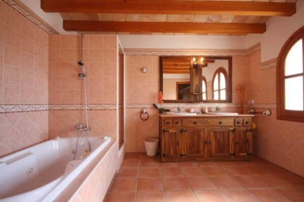 A bathroom with a bathtub, wooden vanity, and a large mirror.
