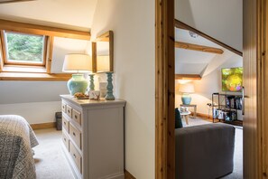 A cozy room with a dresser, a lamp, and a bookshelf.