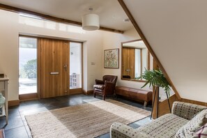 A spacious living area with a large sliding door, a leather sofa, a patterned rug, and a wooden bench.