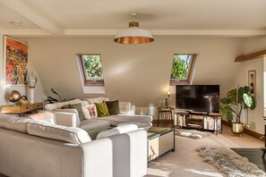 A modern living room with a sectional sofa, a flat-screen TV, and a large window.