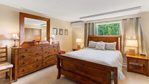 Une chambre à coucher avec un lit en bois, une commode, une chaise et une table de chevet avec une lampe.