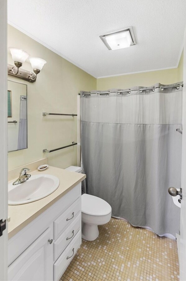 A bathroom with a toilet, sink, and shower curtain.