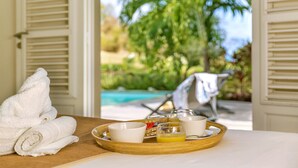 A breakfast tray with a towel, a bowl, a cup, and a glass of orange juice on a wooden table. - Areca Palm - luxury villa with private pool, sea and countryside views (Le Vauclin)