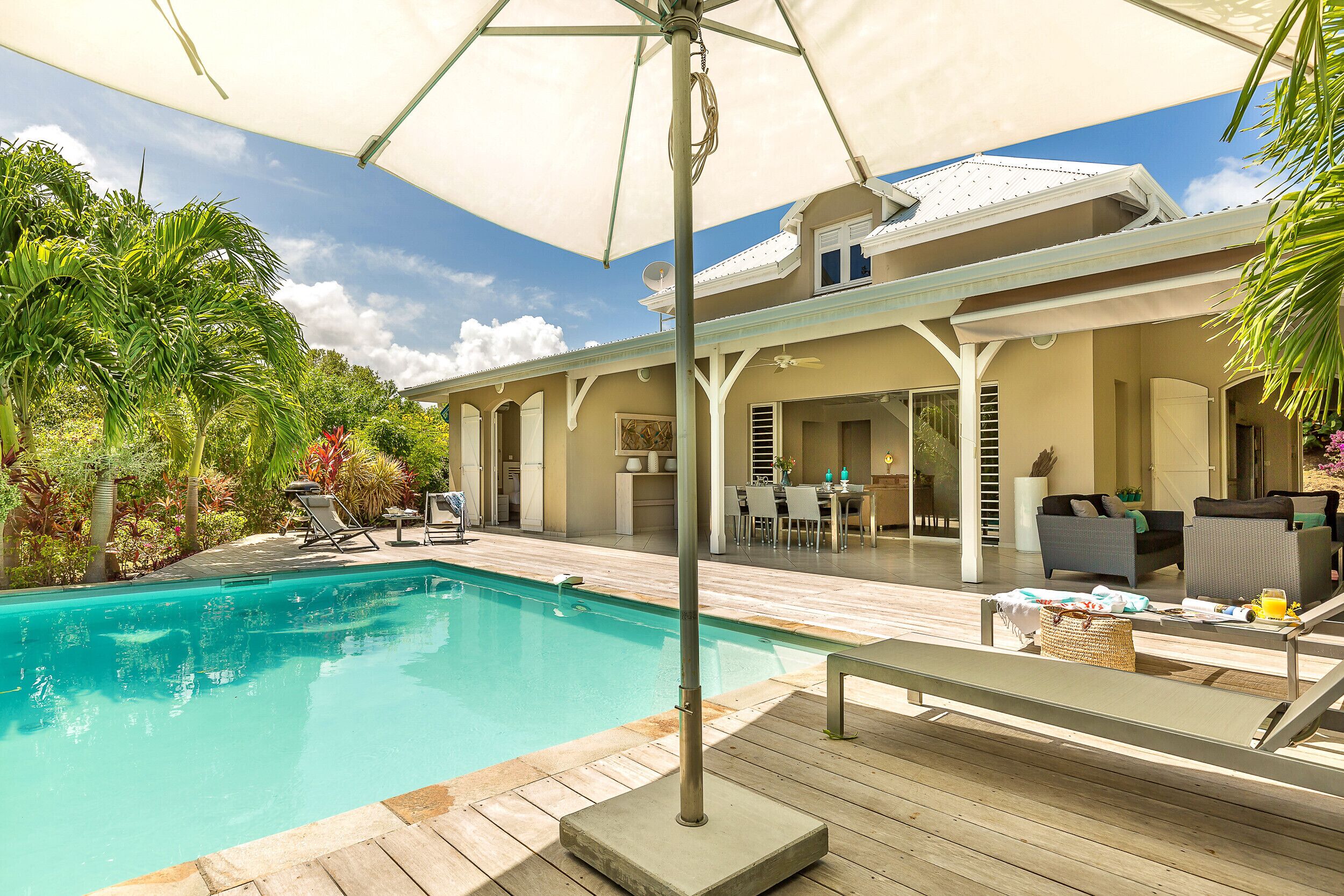 A pool area with a covered patio, lounge chairs, and a dining area.