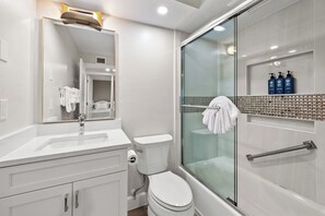 A modern bathroom with a glass shower enclosure, a white sink, and a toilet.