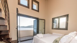 Une chambre à coucher avec un lit, une fenêtre et une porte donnant sur un balcon avec vue sur la mer.