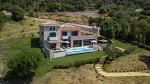 Une maison moderne à deux étages, dotée d’une piscine, entourée d’une pelouse bien entretenue et d’arbres.