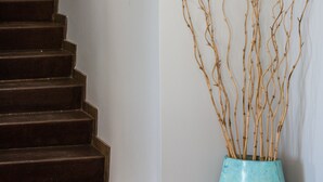 Un escalier avec un vase bleu contenant des branches, placé sur la plateforme.