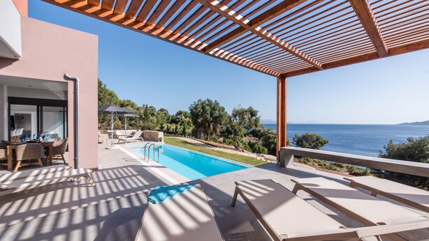 Un espace aménagé au bord de la piscine, avec des chaises longues et une vue sur la mer.