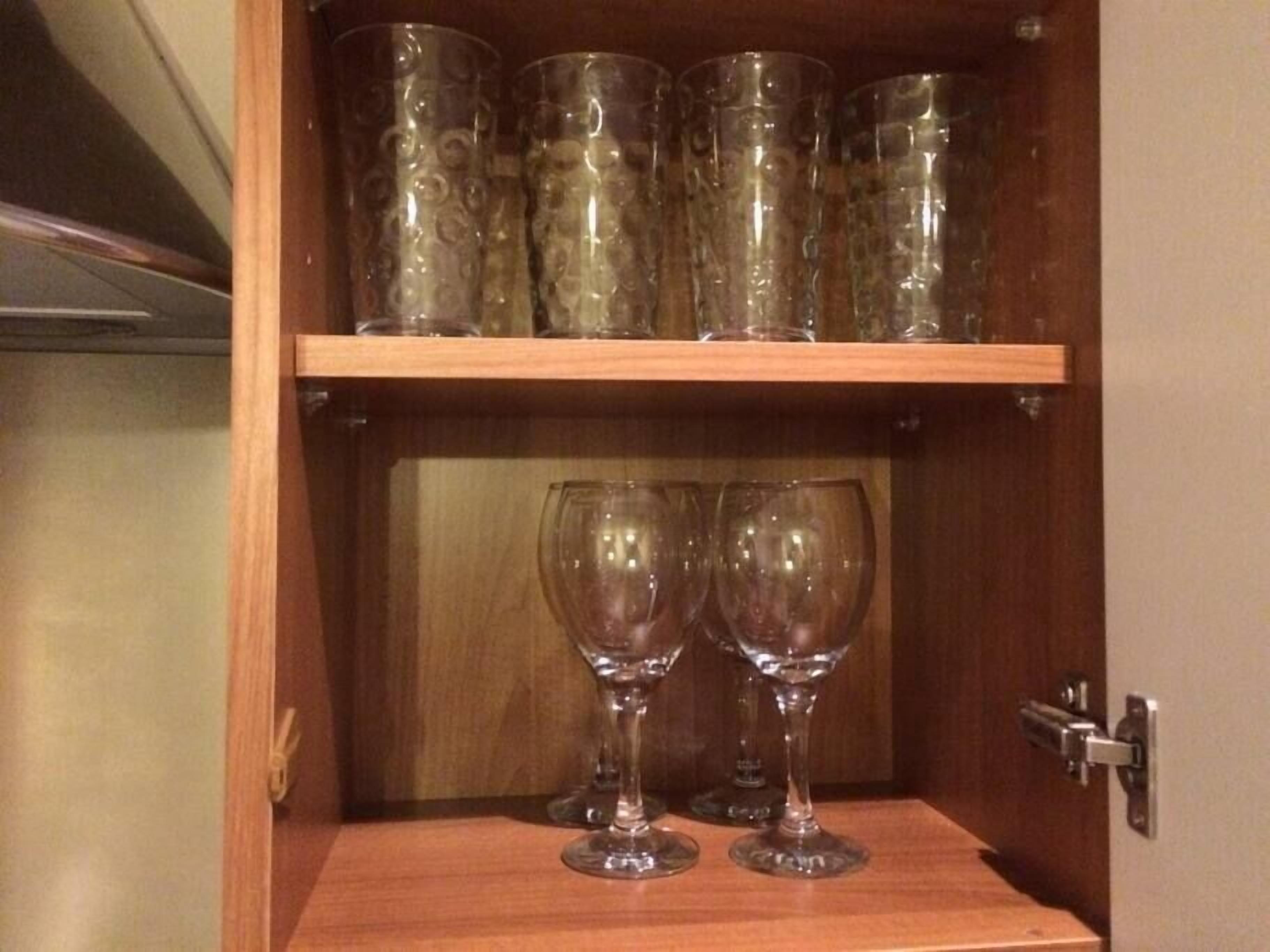 Ein Holzschrank mit zwei Weingläsern in der unteren Etage und mehreren Gläsern in der oberen Etage.