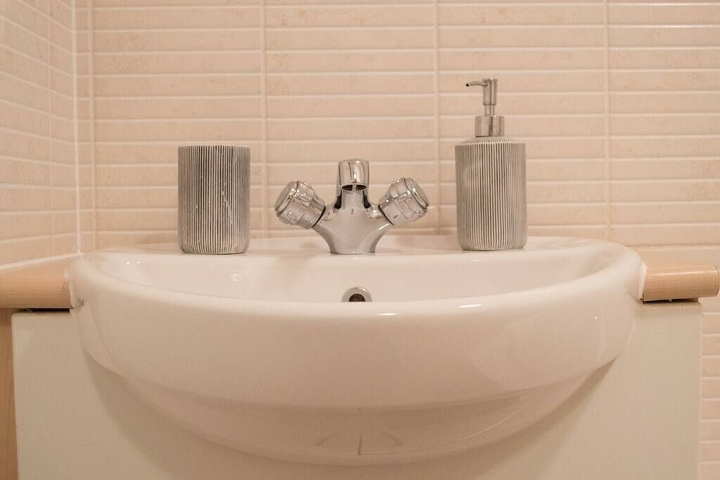 Ein Waschtisch mit einem modernen Wasserhahn und zwei zylindrischen Seifenspendern.