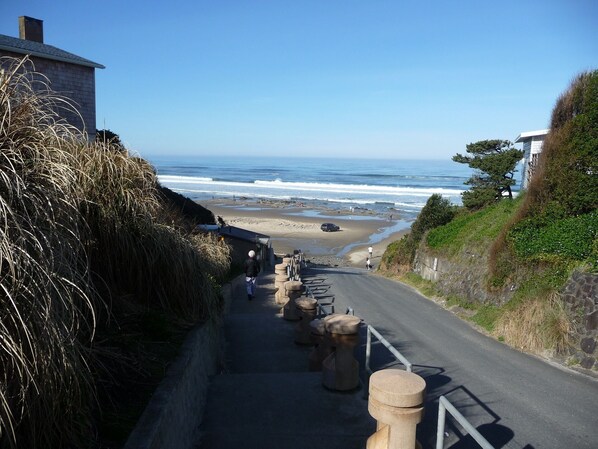 A coastal road with stone bollards, leading to a beach.