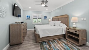 A bedroom with a bed, nightstands, a dresser, a ceiling fan, and a TV mounted on the wall. - Newly Renovated Garden View 2 bed, 2 bath at Sanibel Moorings #641 (Sanibel)