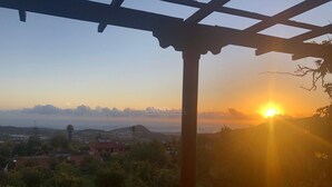 Vista del atardecer desde un espacio exterior cubierto con estructura de pérgola.