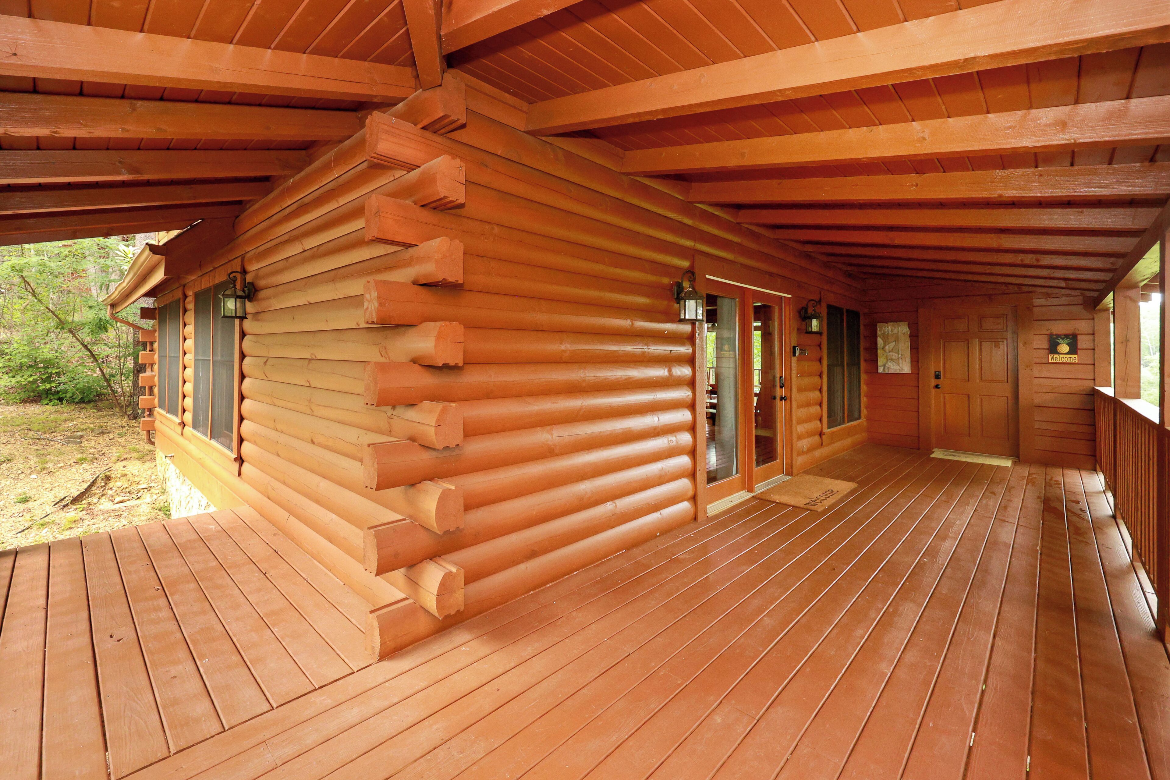 Een houten blokhut met een terras en een overdekte veranda.