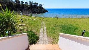 A pathway leading to a beach with a clear view of the ocean and a rocky cliff in the background. - Family Holiday with spectacular sea views · UHC ARINSAL (Salou)