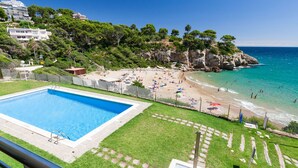 A pool area with a clear blue pool, surrounded by a fenced grassy area. - Family Holiday with spectacular sea views · UHC ARINSAL (Salou)
