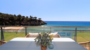 A balcony with a table set for dining, overlooking a beach and the sea. - Family Holiday with spectacular sea views · UHC ARINSAL (Salou)