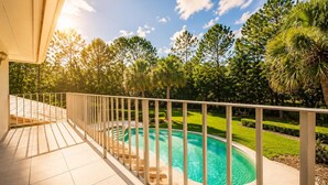 A swimming pool with a wooden deck and railing, surrounded by lush greenery and trees. - SWISS 41 - Golf Course (Clermont)