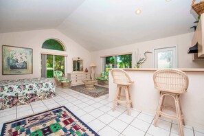 A bedroom with a bed, a dresser, a chair, a small table, and a window with a view of greenery. - SWISS 41 - Golf Course (Clermont)