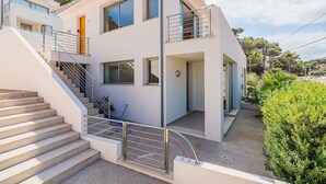 Ein modernes, zweistöckiges Haus mit Treppe, großen Fenstern und einem Balkon.