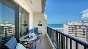 A balcony with a table, chairs, and a view of the ocean.