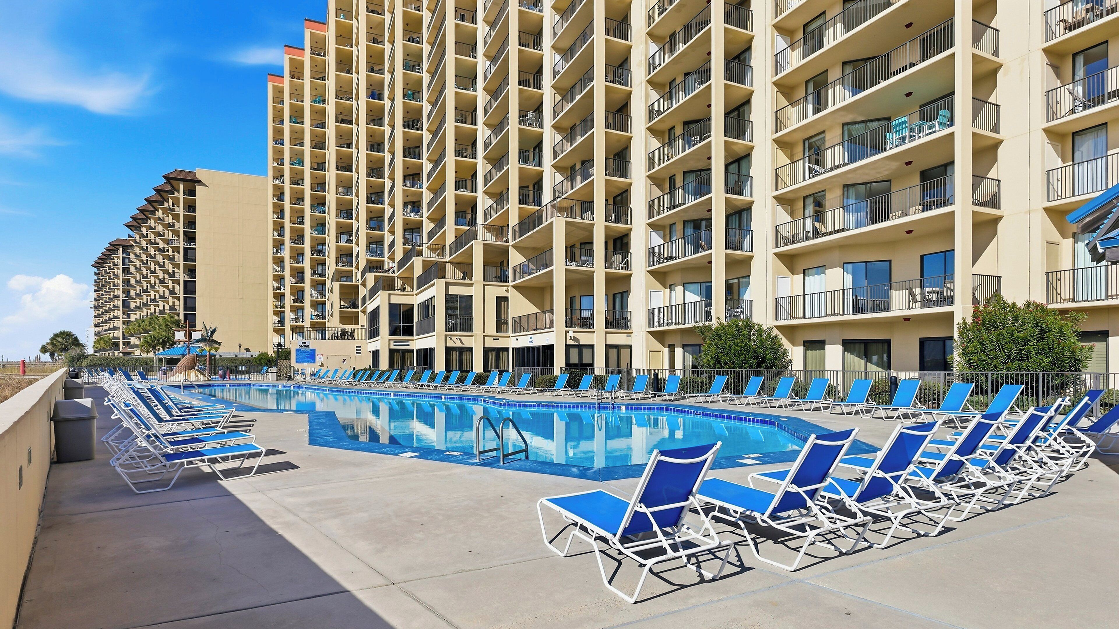 Un hotel con un'ampia area piscina, numerosi balconi e un design architettonico moderno.