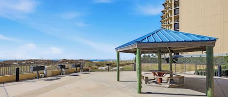 Una terraza en la azotea con un pabellón de techo azul, asientos al aire libre y vistas al océano.