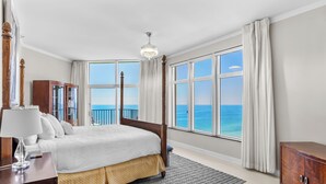 Une chambre spacieuse avec un grand lit, une table de chevet, une commode et une vue sur l’océan.