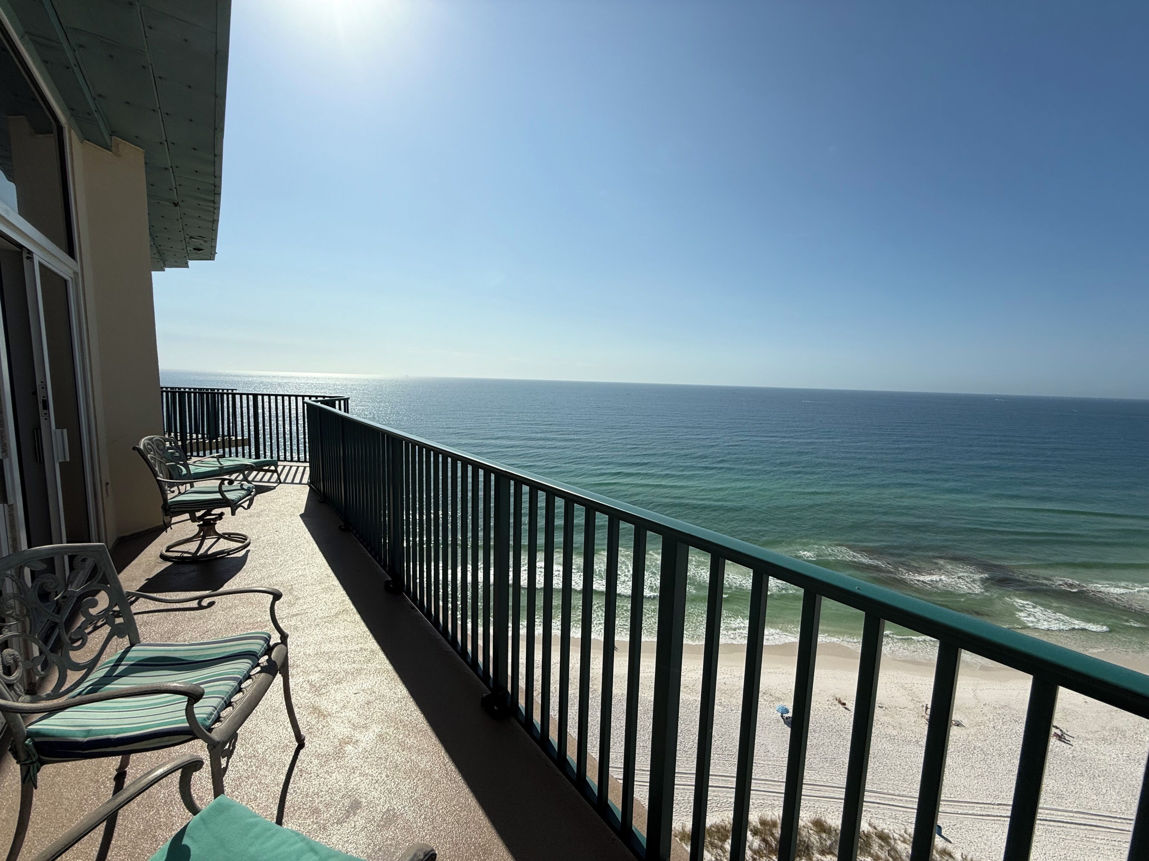 A balcony with two chairs and a table, overlooking the ocean.
