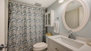 A bathroom with a toilet, sink, mirror, and shower curtain. - Siesta Key Beachfront Vacation Condo - great value and many amenities! (Sarasota)