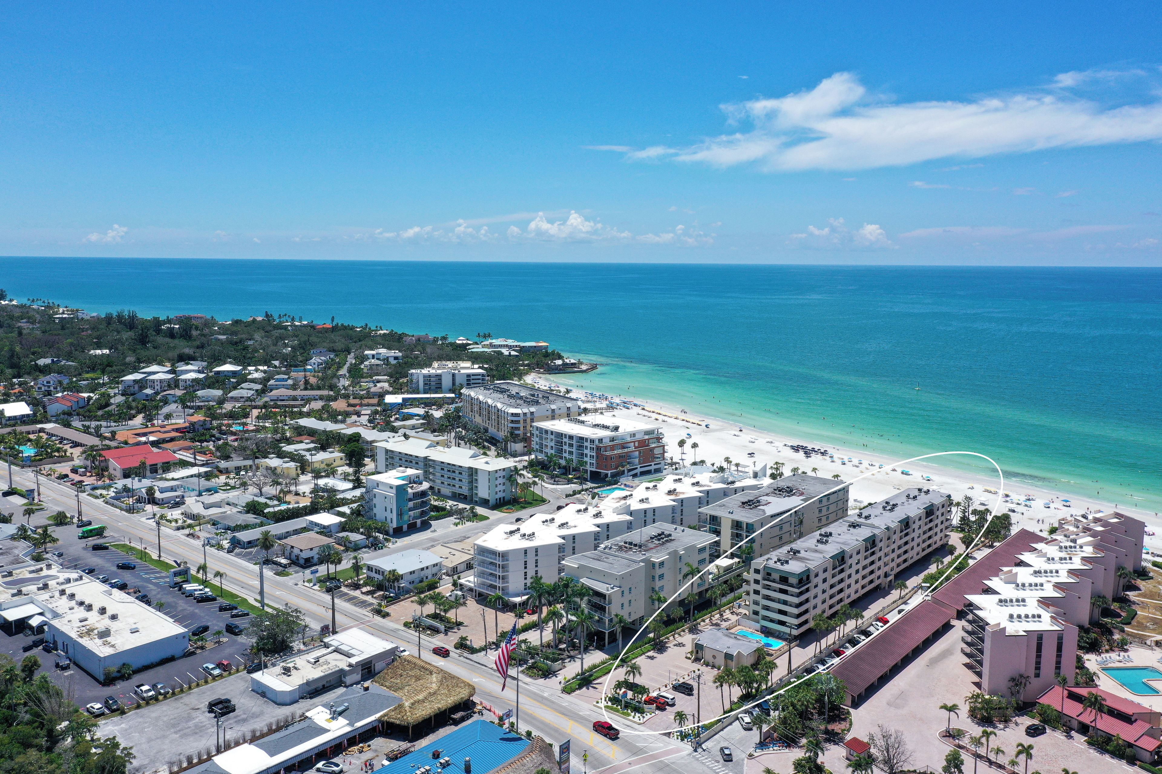 A coastal resort area with beachfront hotels, a clear blue sky, and a calm sea.
