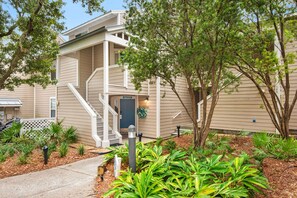 A two-story residential building with a covered porch and a landscaped front yard.