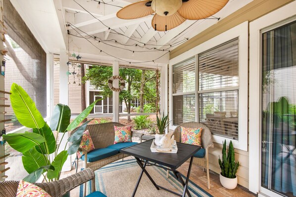 A sunroom with wicker furniture, a table, and potted plants. - Ground Floor, Walk to the Beach, Pool,  Beach Chair Service Included (Miramar Beach)
