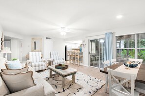 A spacious living room with a sofa, armchairs, a coffee table, and a dining area with a table and chairs. - Ground Floor, Walk to the Beach, Pool,  Beach Chair Service Included (Miramar Beach)
