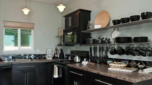 Une cuisine moderne avec des meubles de couleur sombre, un plan de travail en granit et un meuble à bouteilles.