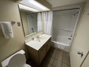 Ein Badezimmer mit Toilette, Waschbecken, Spiegel und Badewanne.