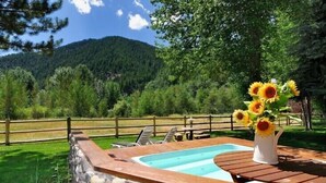 A pool area with a stone wall, wooden deck, and a vase of sunflowers. - Great 2 bed condo, Private deck & hot tub.  Best location in Ketchum! (Ketchum)