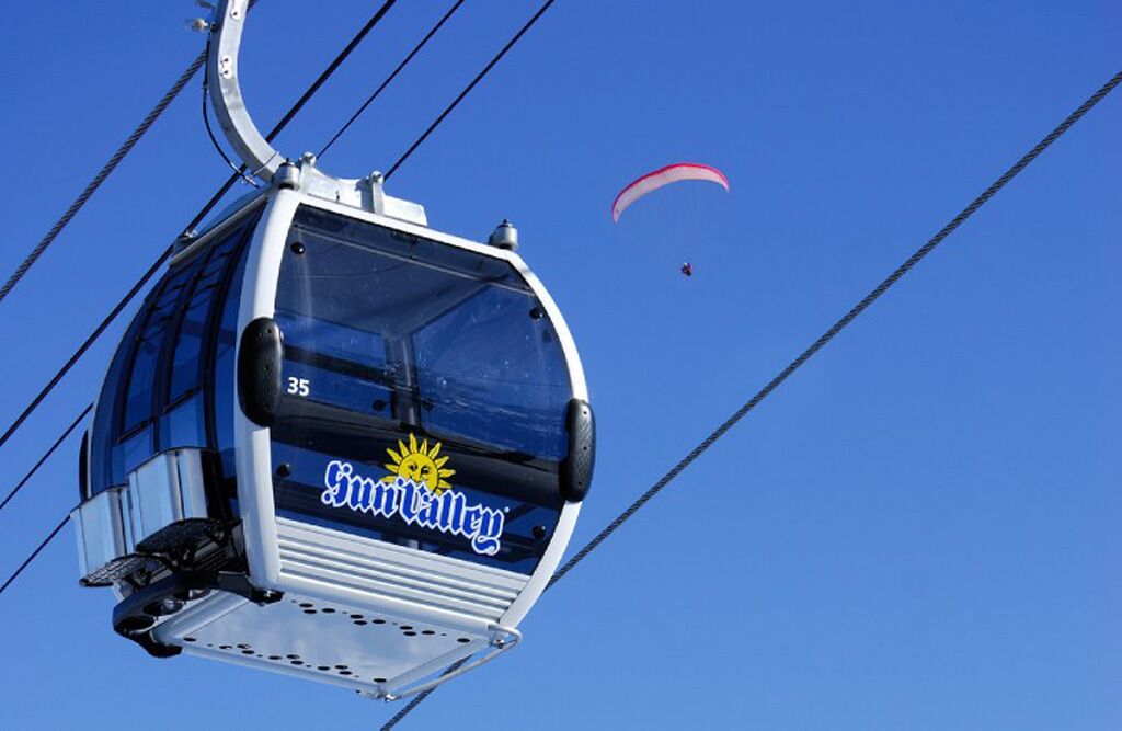 A cable car with the number 35 and the name 'Sun Valley' on it, suspended by cables against a clear blue sky.