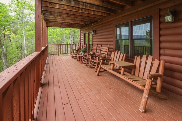 A wooden deck with outdoor seating and large windows. - Beautiful Mountain View Overlooking The Smokies! Hot Tub, Pool Table, Mini Golf (Sevierville)